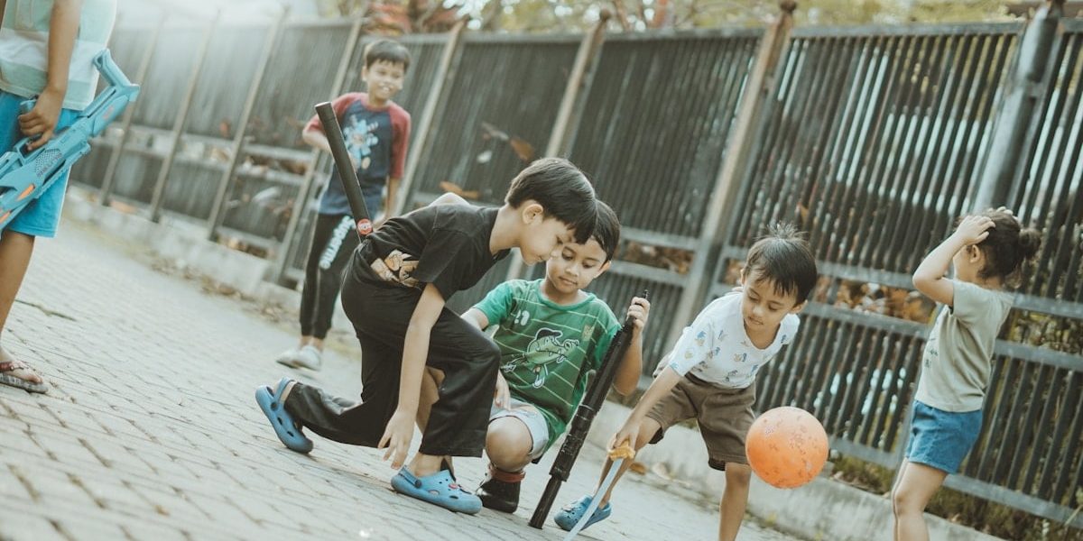 Children play together with a ball and sticks.