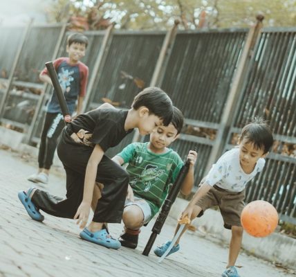 Children play together with a ball and sticks.